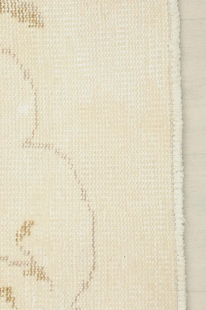Close-up of the rug's edge, revealing the cotton foundation and the finish of the hand-knotted wool