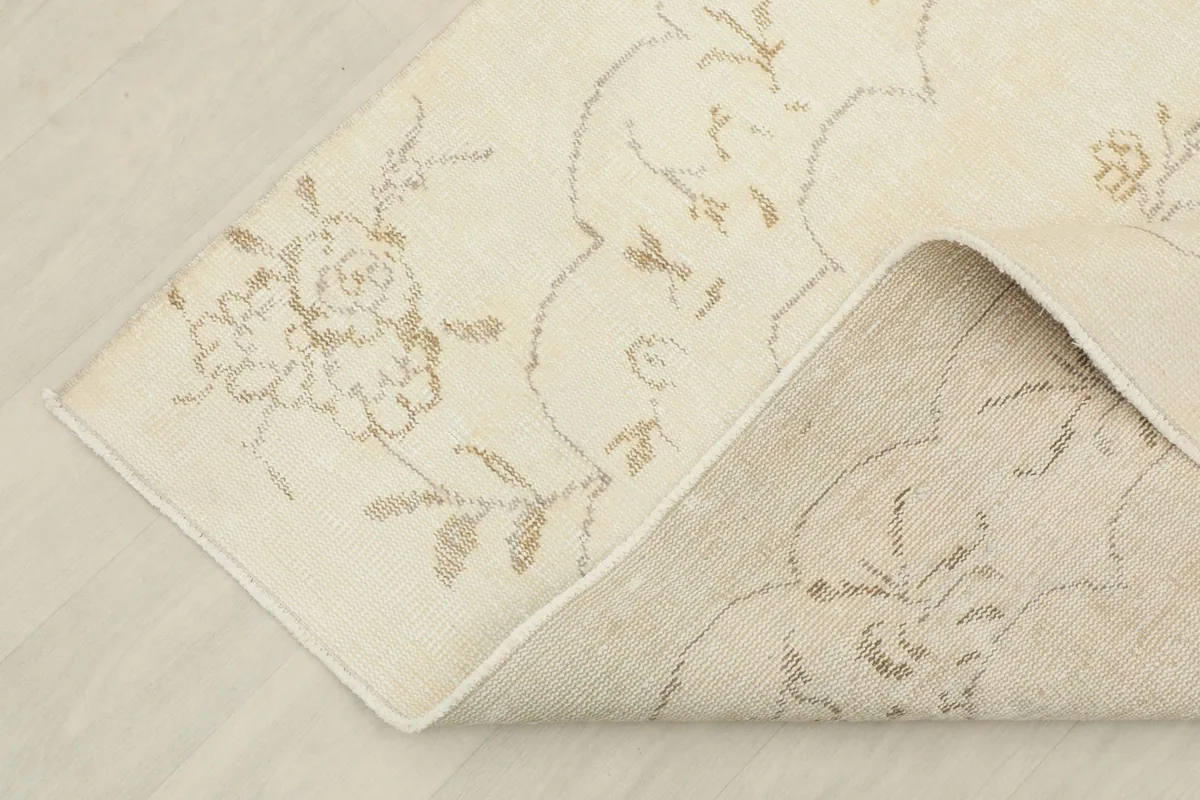 Corner of the rug folded back to show the cotton foundation and the reverse side of the hand-knotting