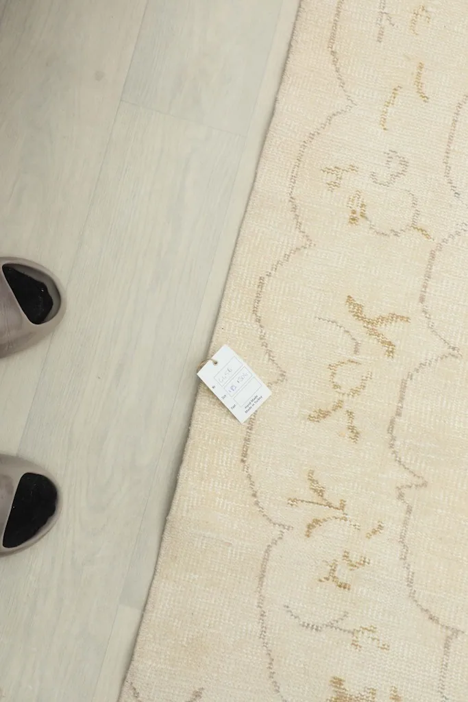 Overhead view showing the rug with a size tag and a pair of slippers for scale reference