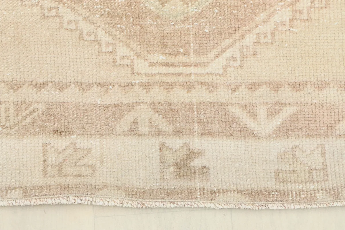 Detail of the rug's border and fringe, showcasing the hand-knotted craftsmanship and edge wear.