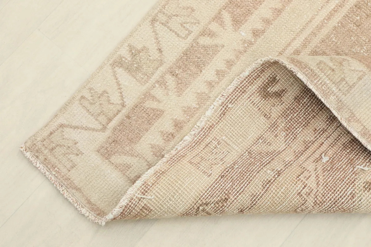 Corner of the rug folded to show the back of the hand-knotted wool pile on cotton foundation.