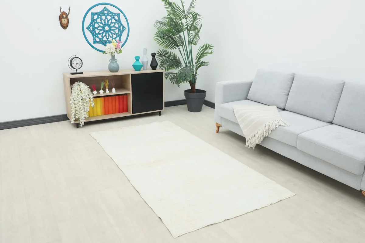 Cream vintage Anatolian runner placed in a modern living room setting with a light gray sofa and wooden cabinet.
