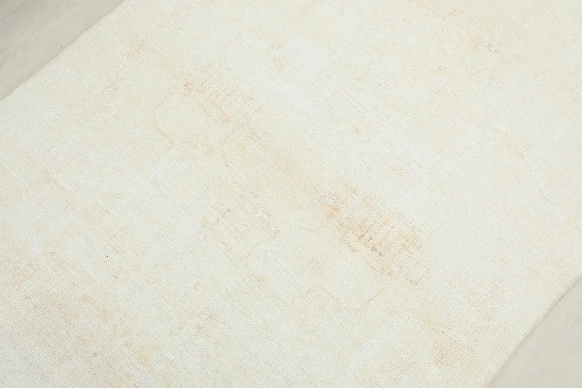 Detailed view of the rug's surface, revealing the very faint, faded geometric patterns and slight patina.