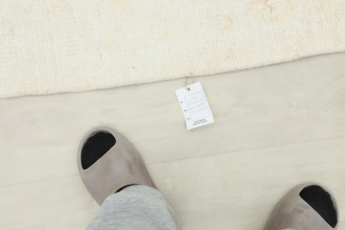 Overhead view of a foot next to the rug with a product tag, indicating the rug's size and quality.