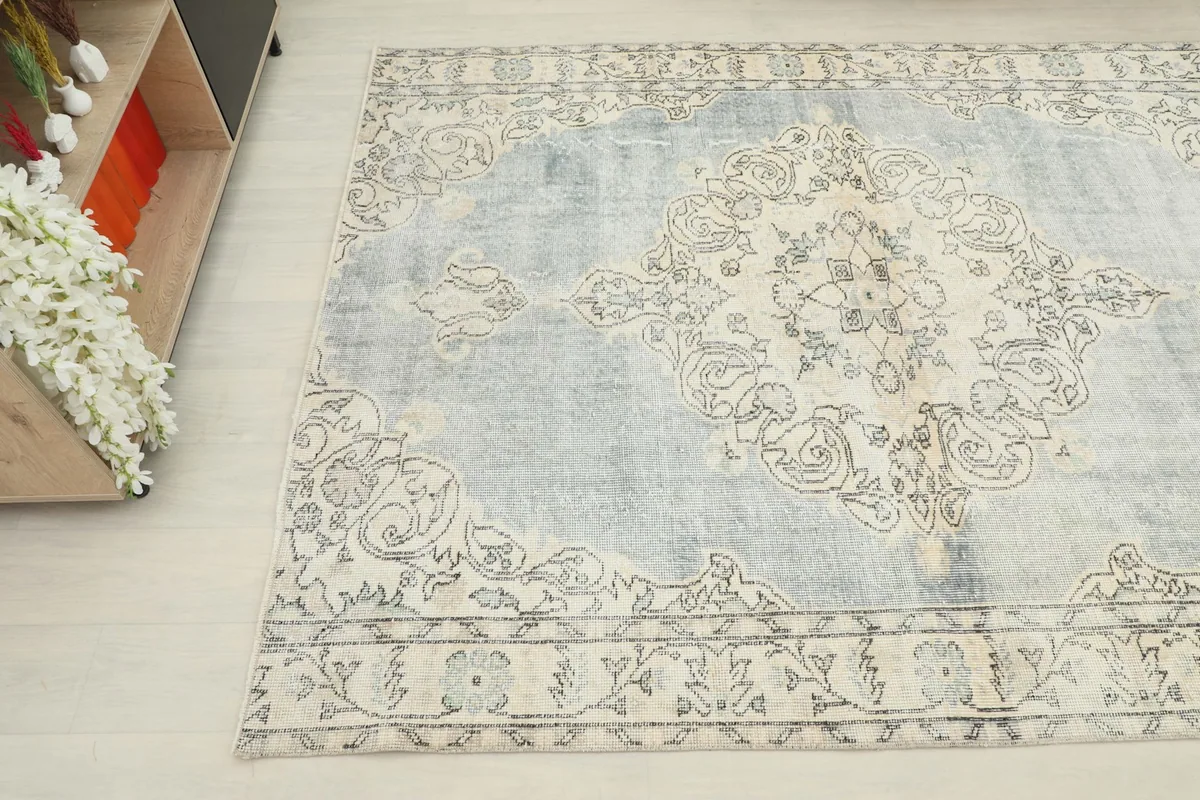 Angled shot of the vintage rug, showing the faded gray and cream colors with natural wear