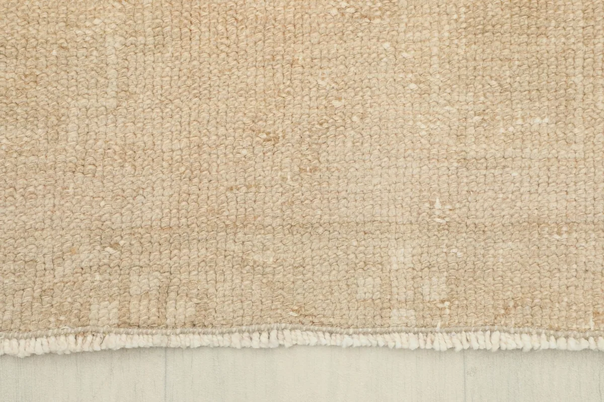 Detail of the short, natural fringe and the finished edge of the tan runner rug.