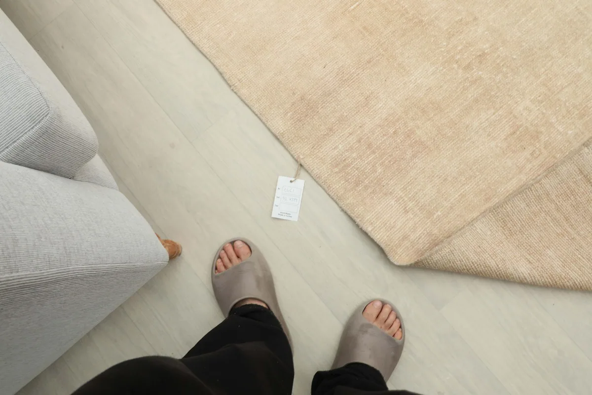 Overhead view showing a person's feet next to the tan runner rug, indicating scale.