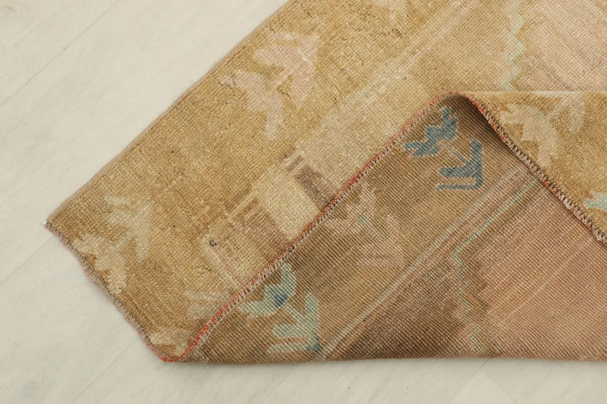 Corner of the rug folded to show the hand-knotted back and wool pile texture