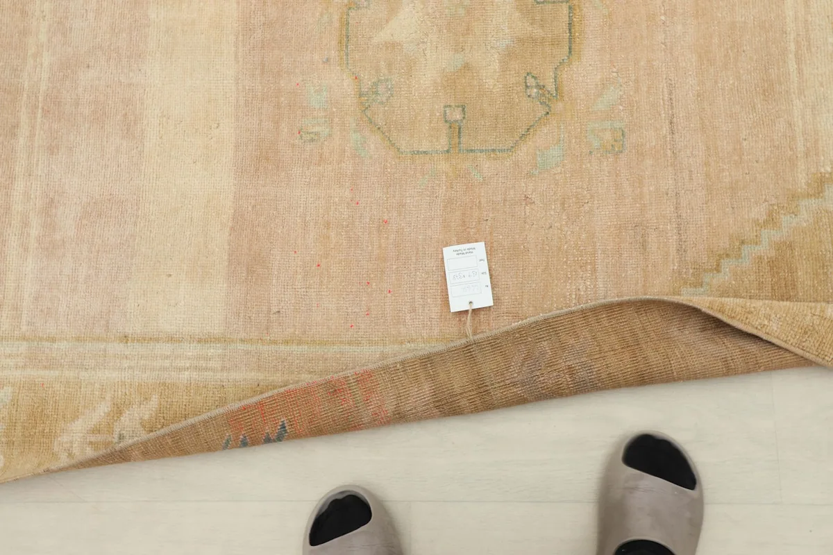 View of the rug with a size tag and feet for scale, showing the low pile