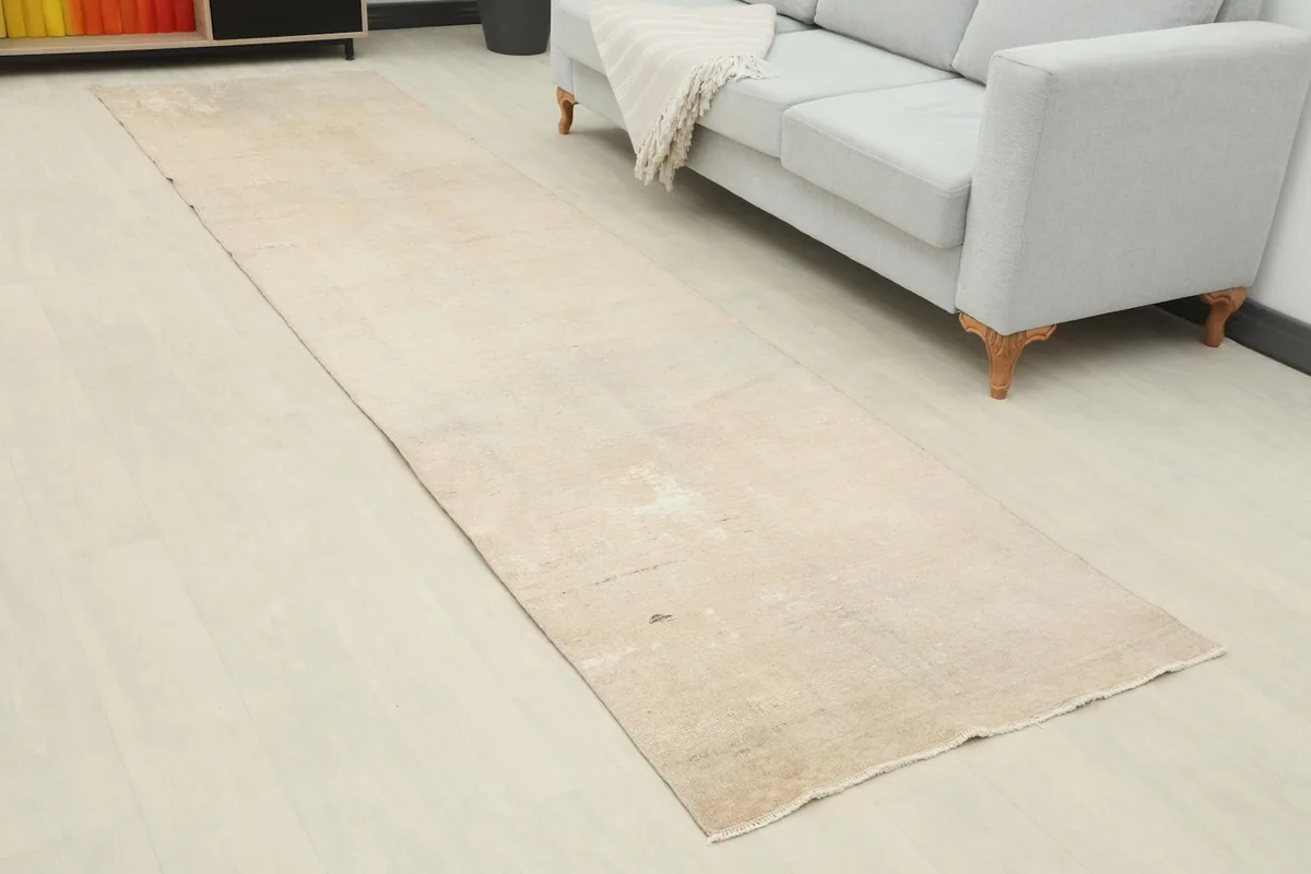 Angled view of the beige runner rug extending from a bookshelf towards a light gray sofa