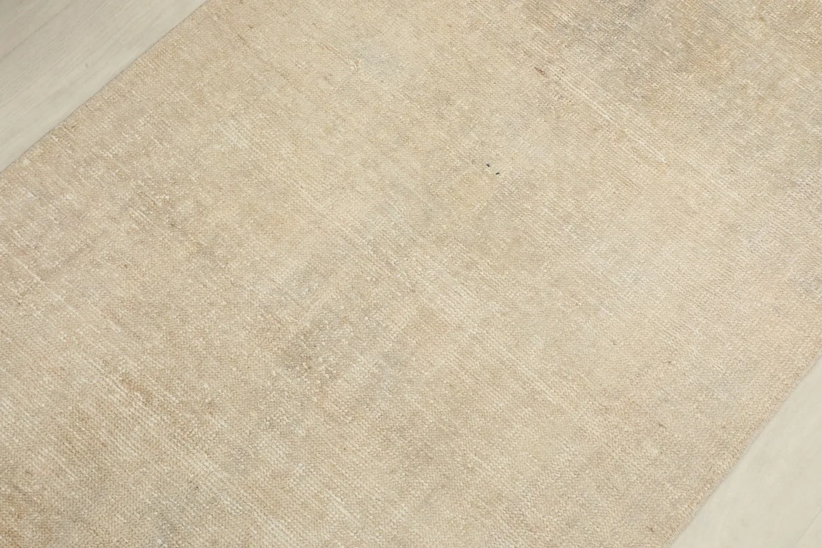 Close-up view of the rug's surface, revealing the subtle geometric patterns within the beige and tan fibers