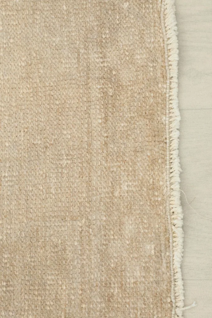 Edge of the runner rug showing the woven side finish and short, natural fringe