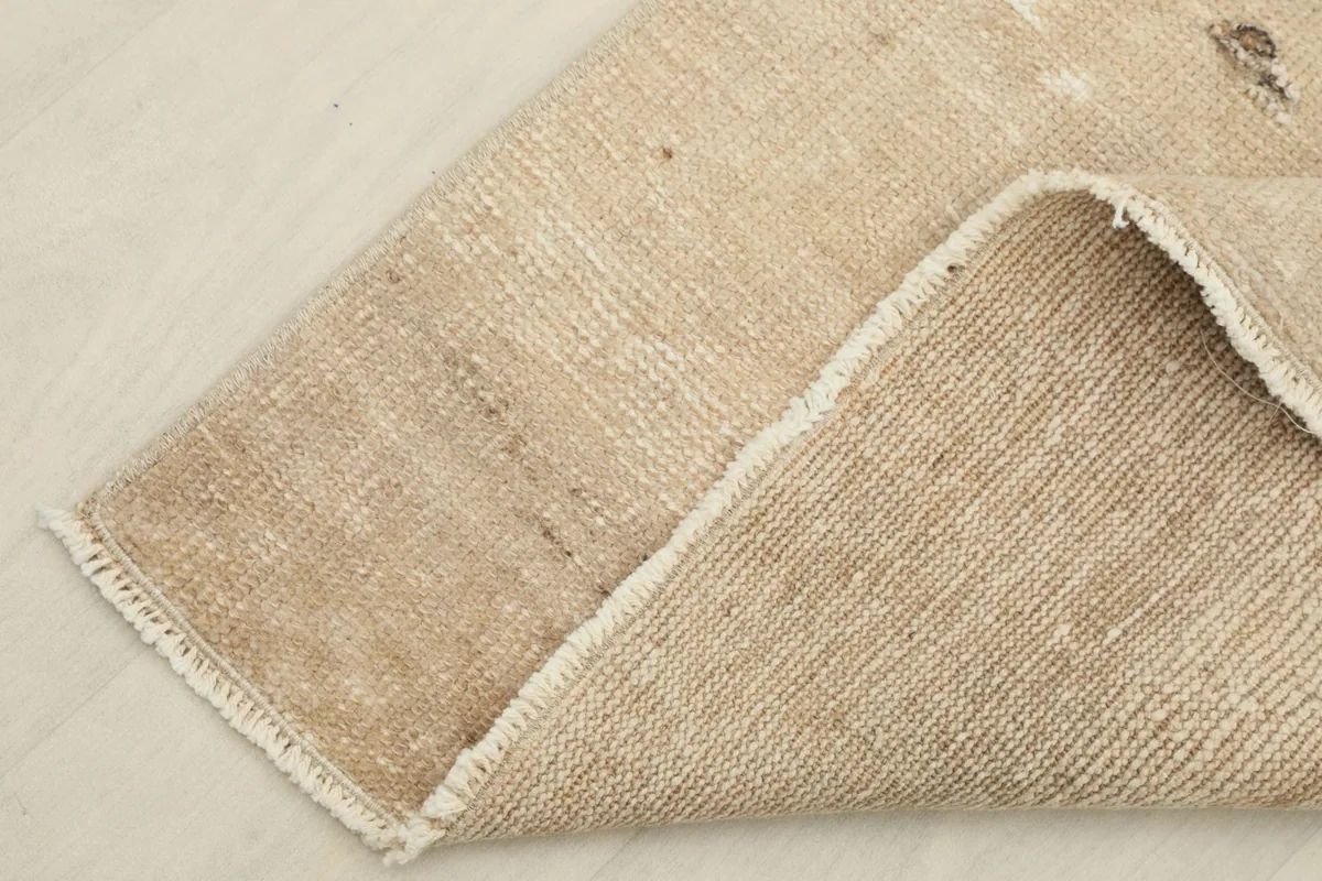 Corner of the rug folded to show the cotton foundation and the reverse side of the hand-knotting