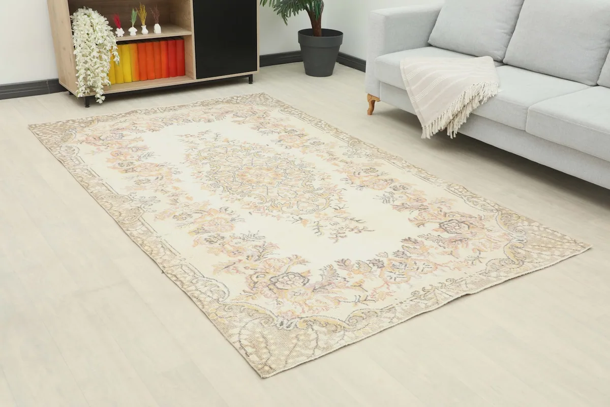 Angle view of the ivory floral rug in a living space, showing its medium size in relation to the sofa and cabinet.