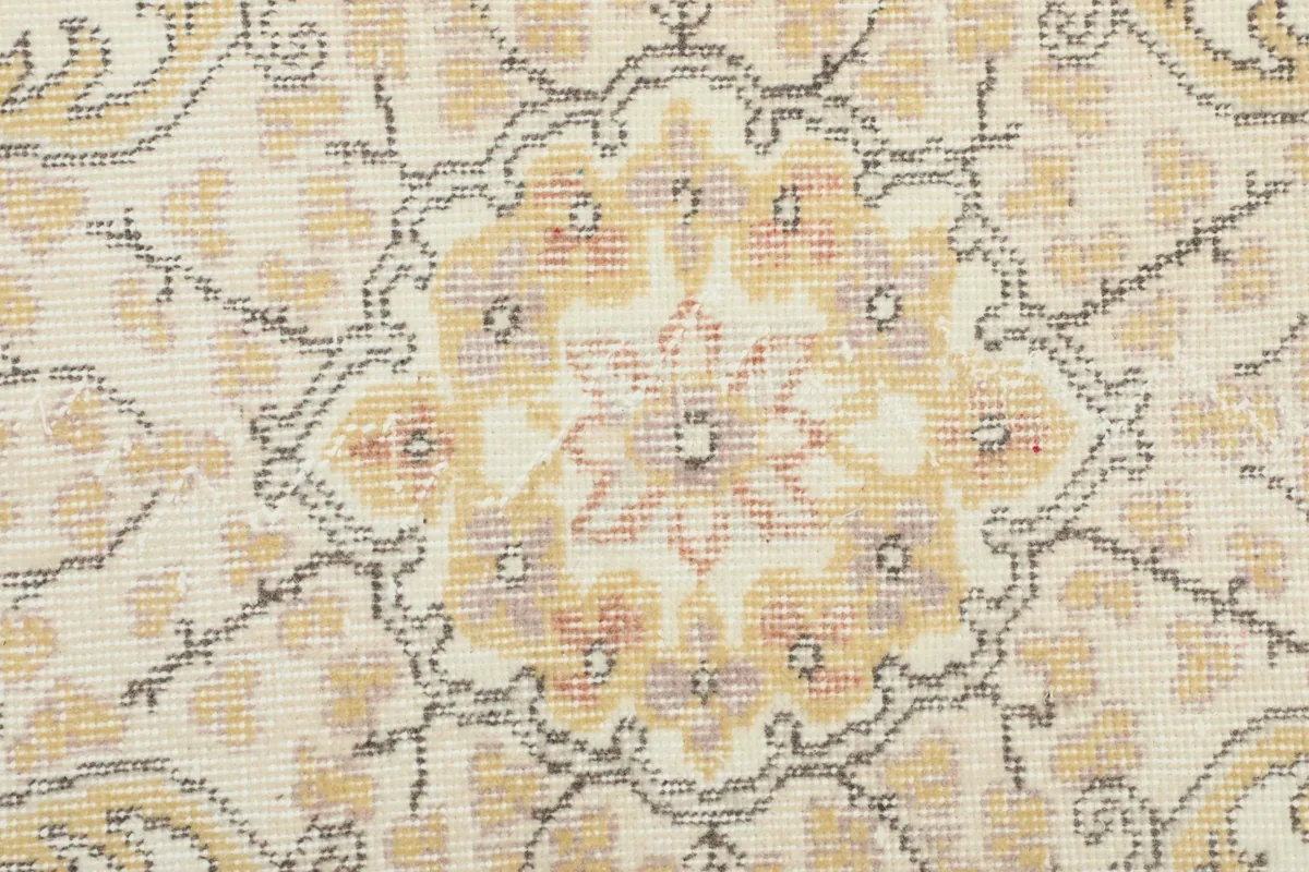 Macro shot of the hand-knotted wool pile, showing the texture and the faded colors of the vintage rug.