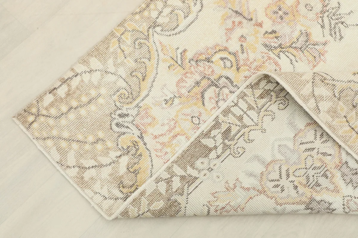 Corner of the rug folded back, showing the back of the hand-knotted cotton foundation and wool pile.
