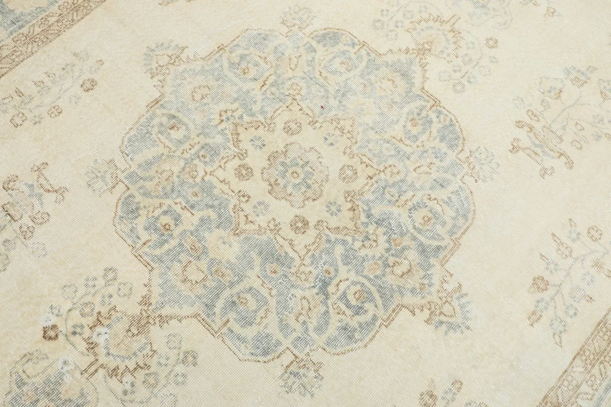 Close-up of the central blue medallion pattern with tan accents on the ivory field