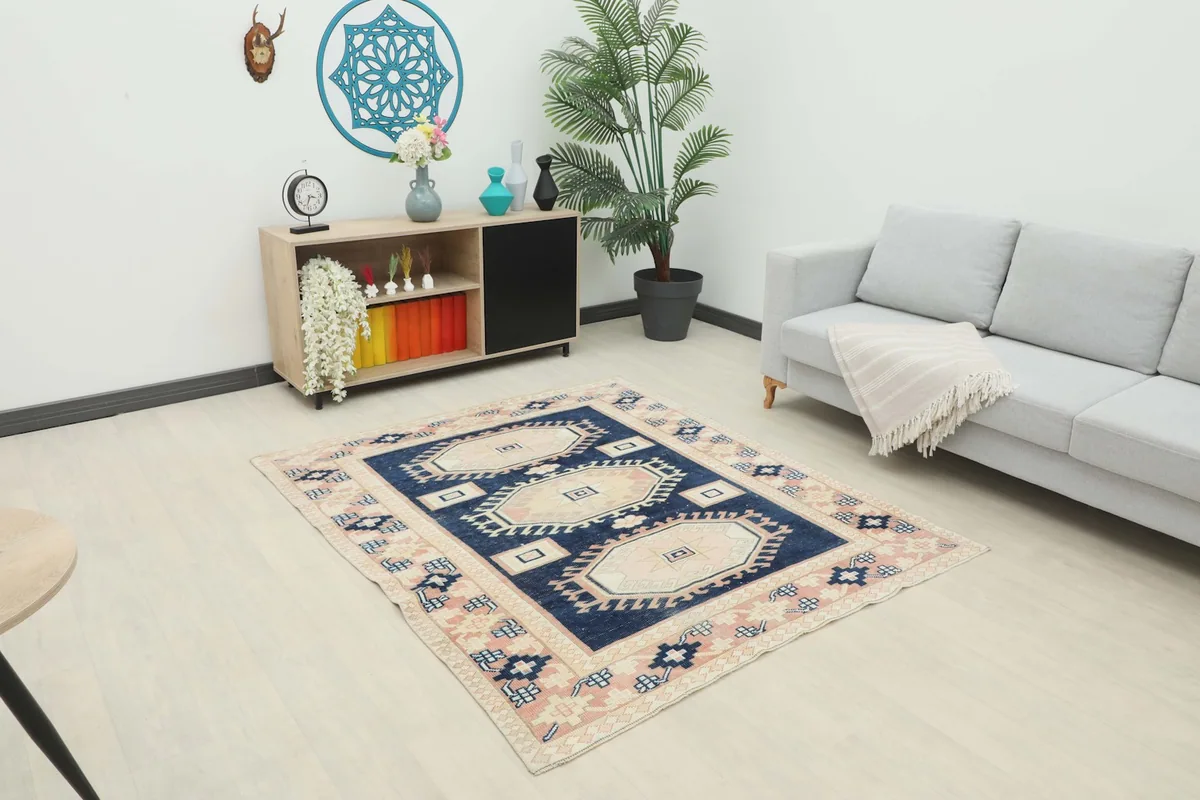 Vintage Anatolian rug displayed in a living room setting with a sofa and cabinet.