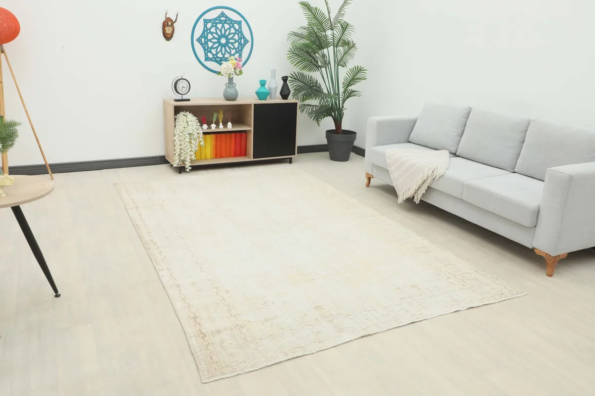 Ivory vintage Anatolian rug displayed in a bright living room setup with a light gray sofa.
