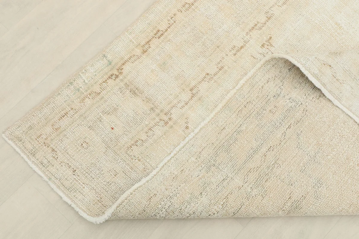 Corner of the rug folded back to reveal the cotton foundation and the reverse side of the hand-knots.