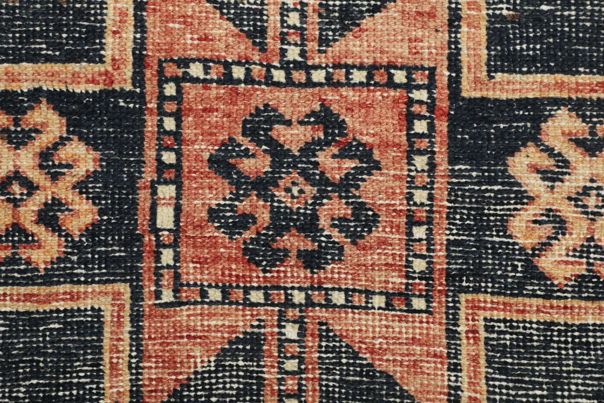 Close-up of a tribal geometric motif with a central design in black on a rust background
