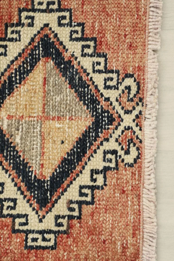 Detail of the rug's short end, showing the diamond motif and the minimal fringe