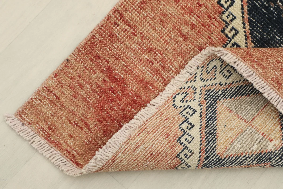 Corner of the rug folded to show the wool pile on cotton foundation and fringe