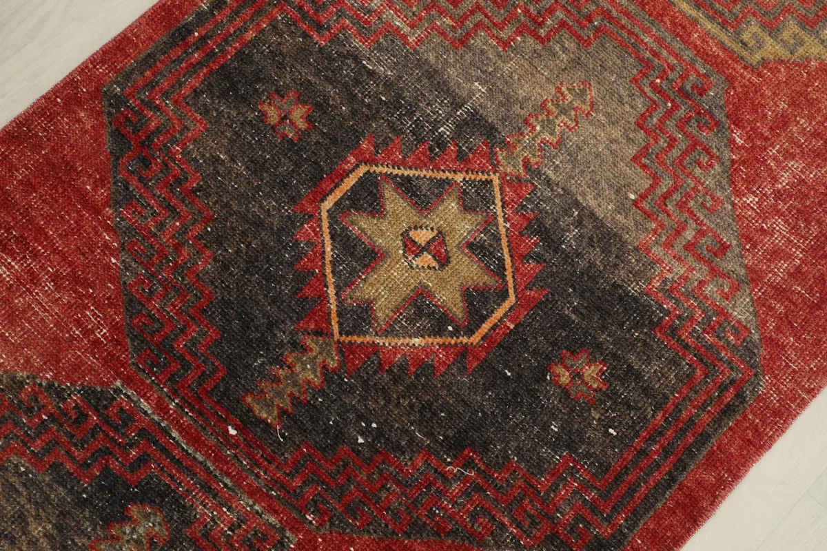 Detailed view of a central charcoal and gold geometric medallion on the red runner