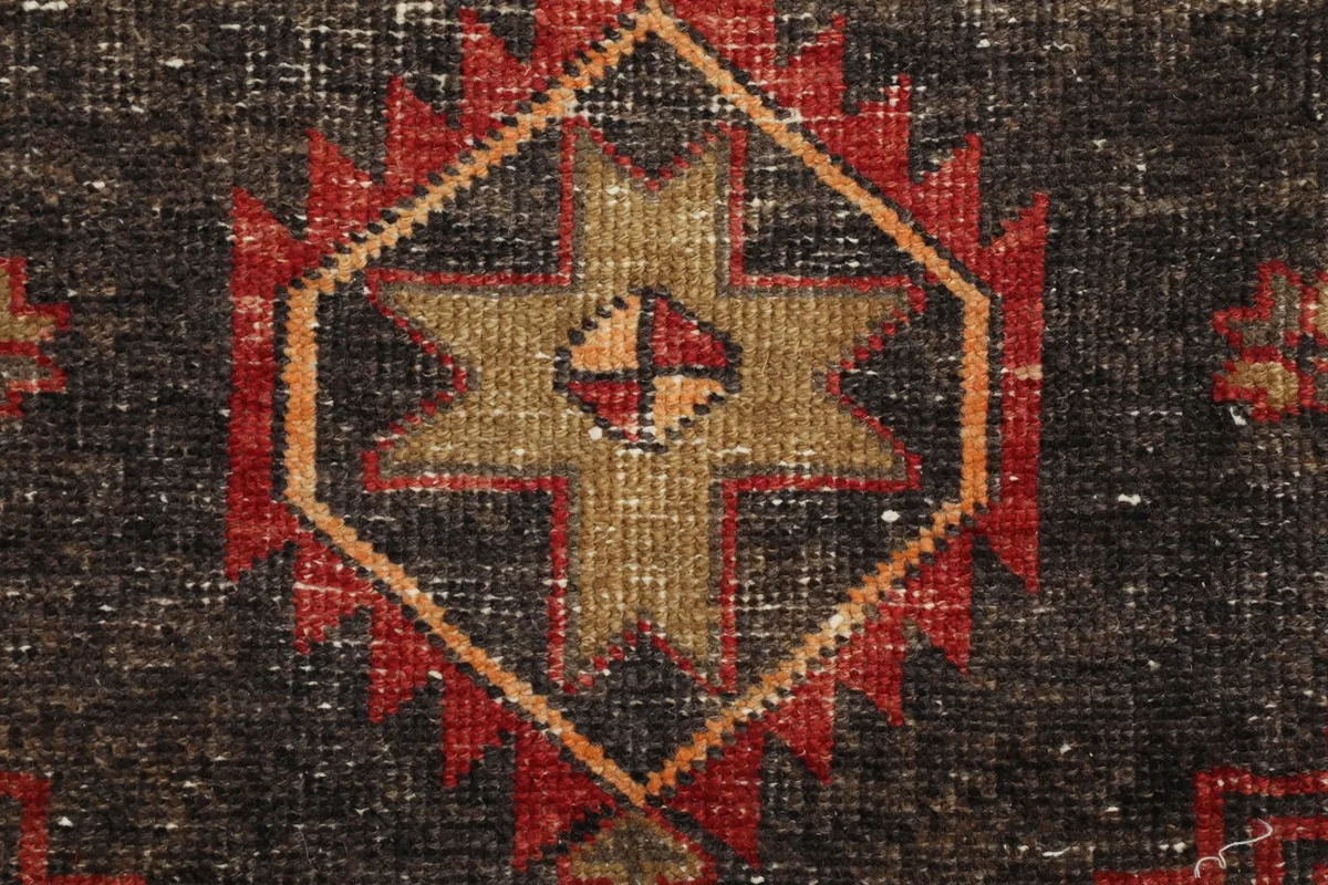 Extreme close-up of a geometric star motif within a charcoal medallion, showing knotting
