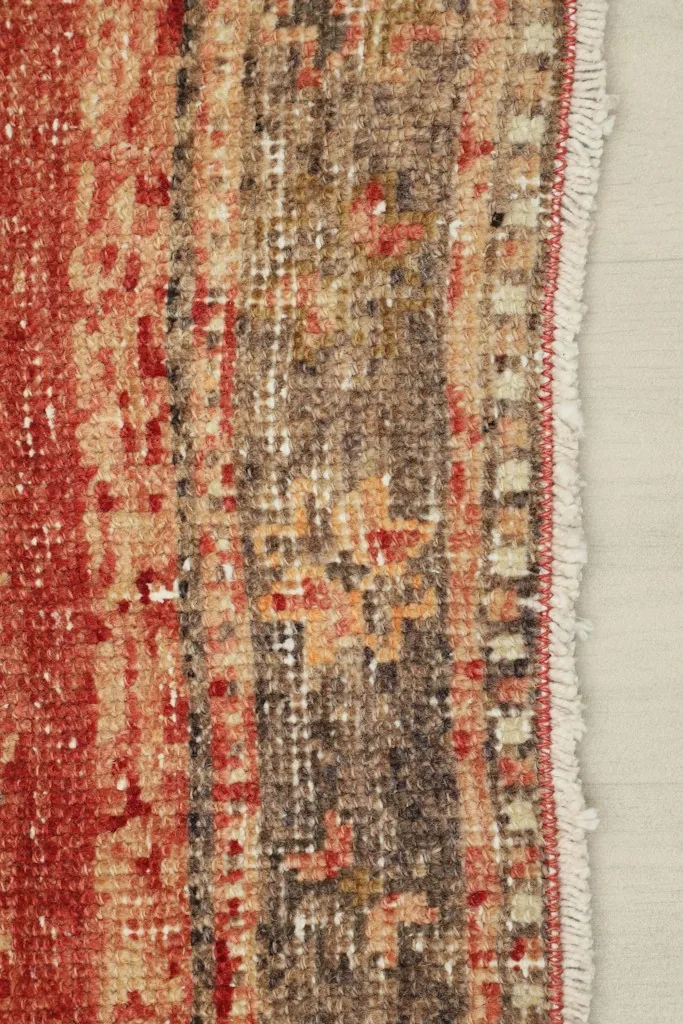 Close-up of the side edge of the runner, showing the fringe and faded border details