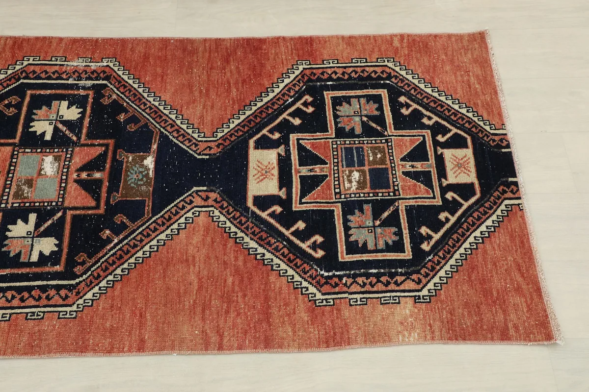 Angled view of the rug's middle section, highlighting the rust field and navy patterns