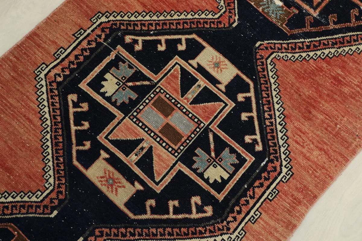 Detailed view of the central navy medallion with geometric patterns in rust, beige, and gray
