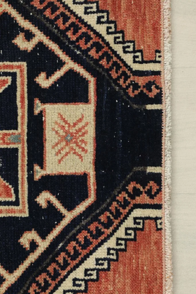 Detail of the rug's edge and fringe, showing the intricate border design and colors