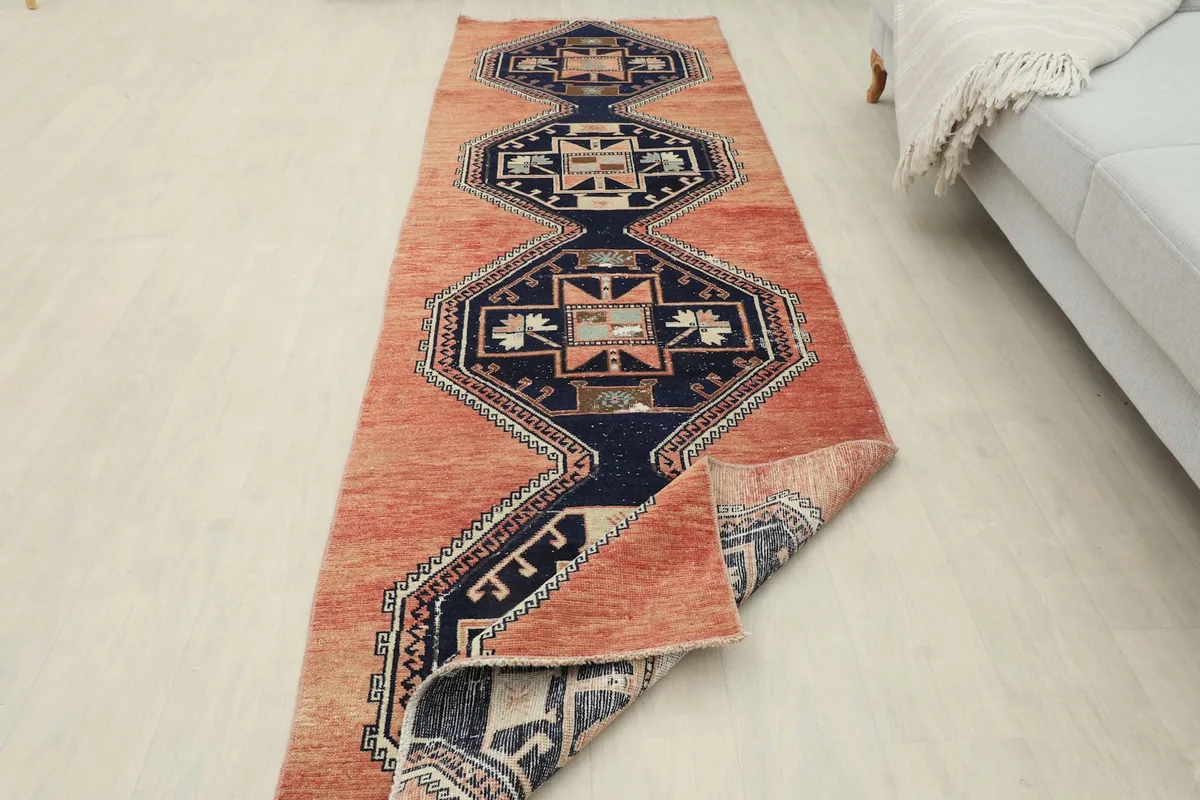 View of the rug partially folded, showing the back and front of the hand-knotted wool