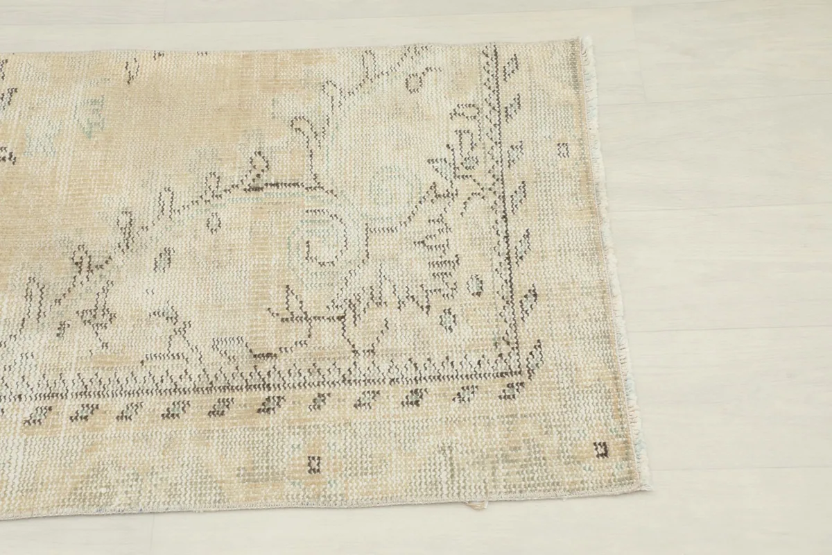 Close-up detail of the rug's border and corner, highlighting the charcoal motifs.