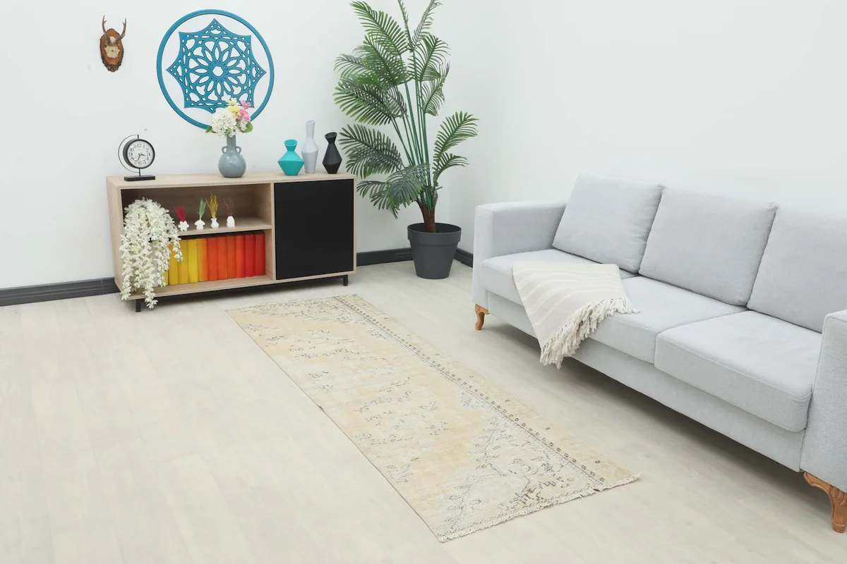 Runner rug in a living room setting with a light gray sofa and wooden cabinet