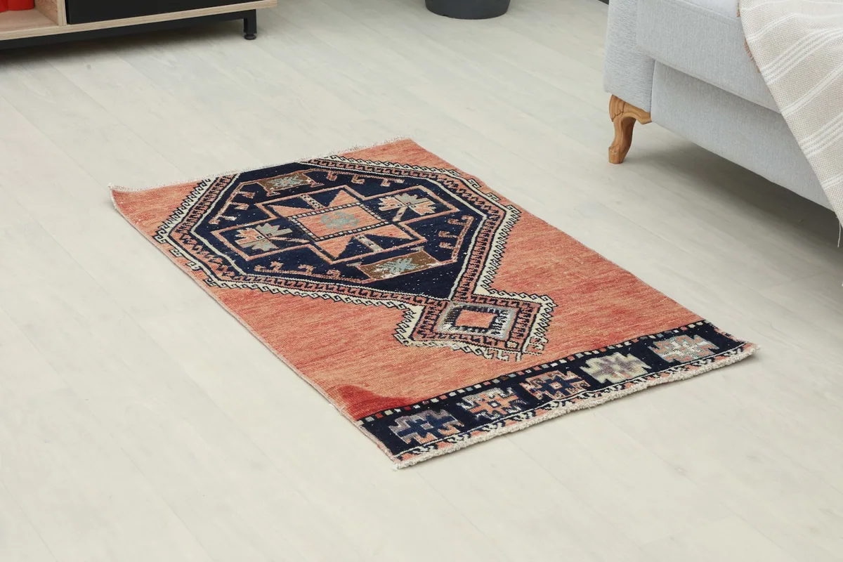 Angled view of the hand-knotted wool rug, highlighting the rust field and navy medallion design