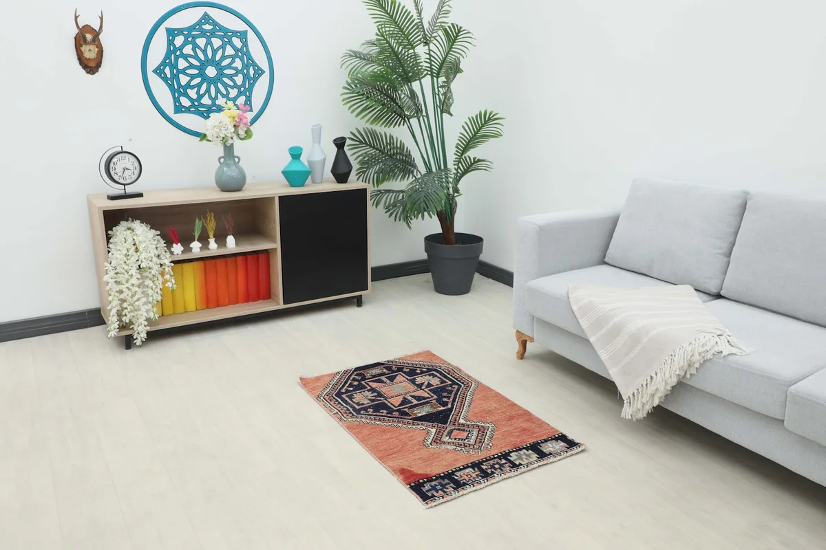 Vintage rust and navy rug placed in a living room setting, showing its scale next to furniture