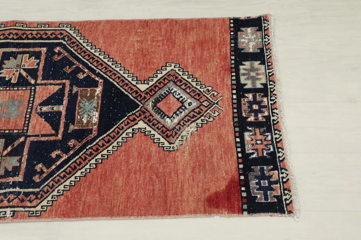 Close-up of the rug's border and a section of the rust field, showing texture and slight wear