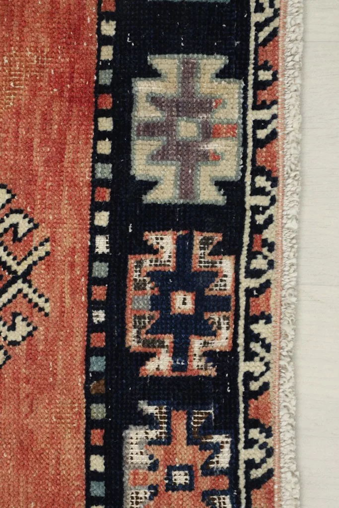 Detail of the rug's side border, featuring navy and beige tribal motifs