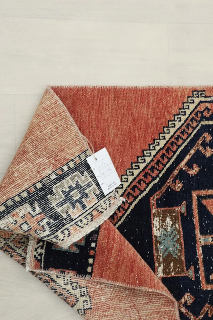 View of the rug's back, showing the tight hand-knotting and a product tag