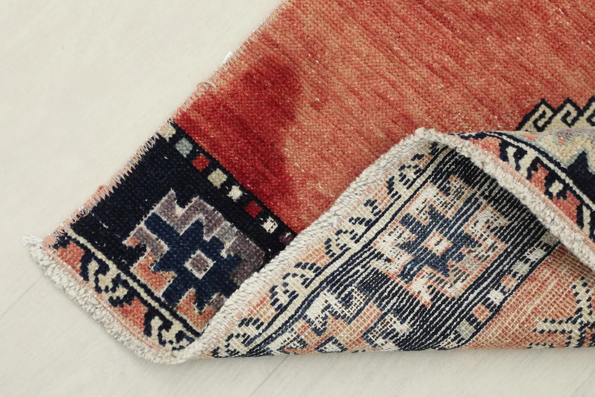 Folded corner of the rug, showing the wool pile texture and cotton foundation