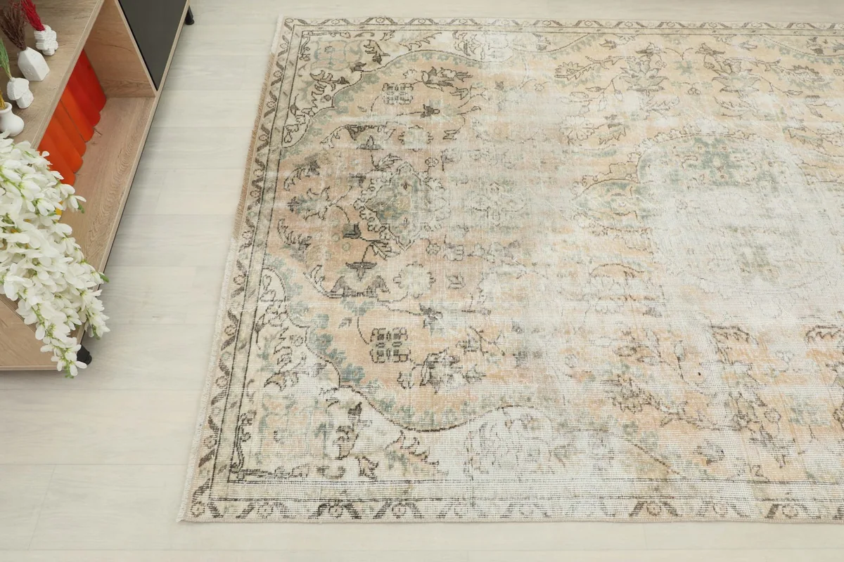 Close-up angled shot of the rug's corner, revealing the intricate faded floral and medallion patterns.