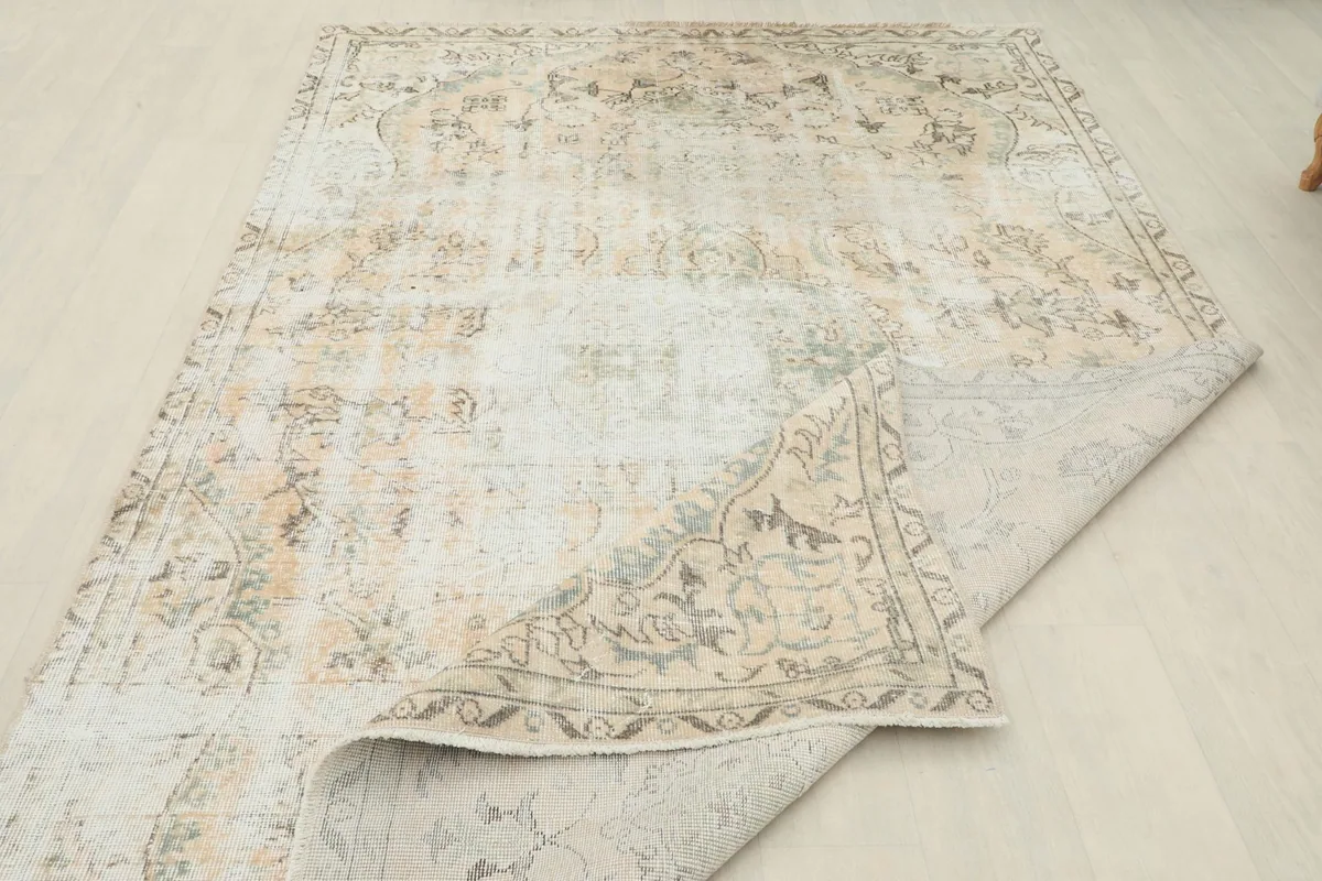 The vintage rug partially folded back, revealing the cotton foundation and the reverse side of the hand-knotted construction.