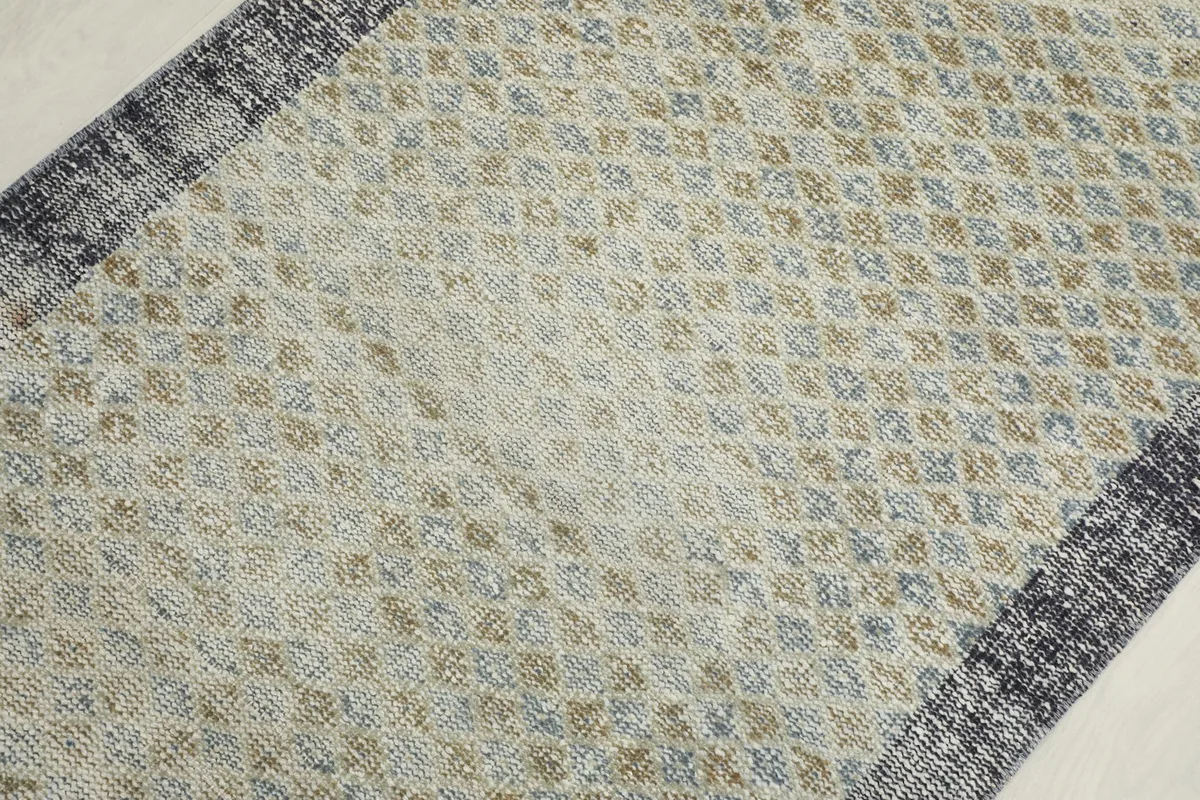 Close-up angled view of the rug's surface, revealing the intricate hand-knotted geometric design.
