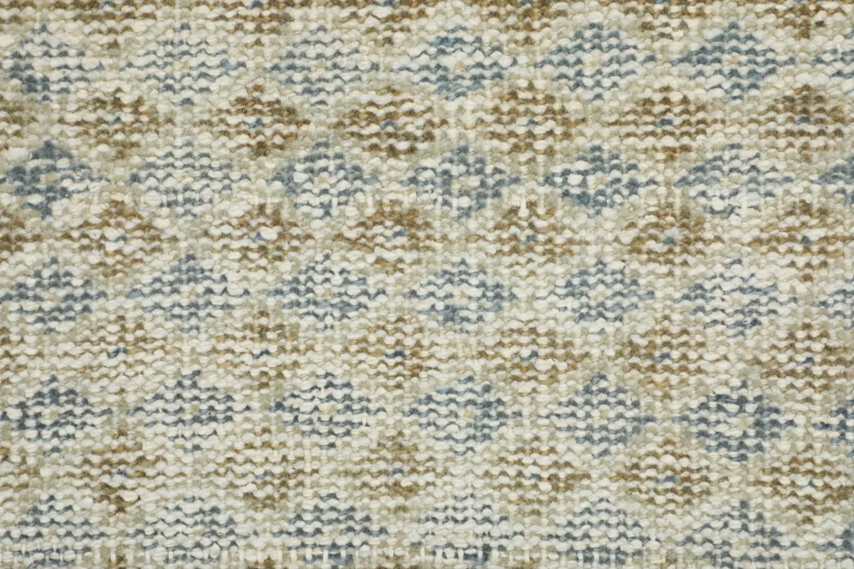 Detailed close-up of the wool pile, showcasing the ivory, blue, and tan diamond geometric pattern.