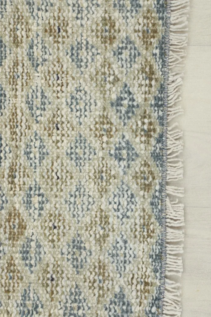 Close-up of the rug's short, natural fringe and the texture of the hand-knotted wool pile.