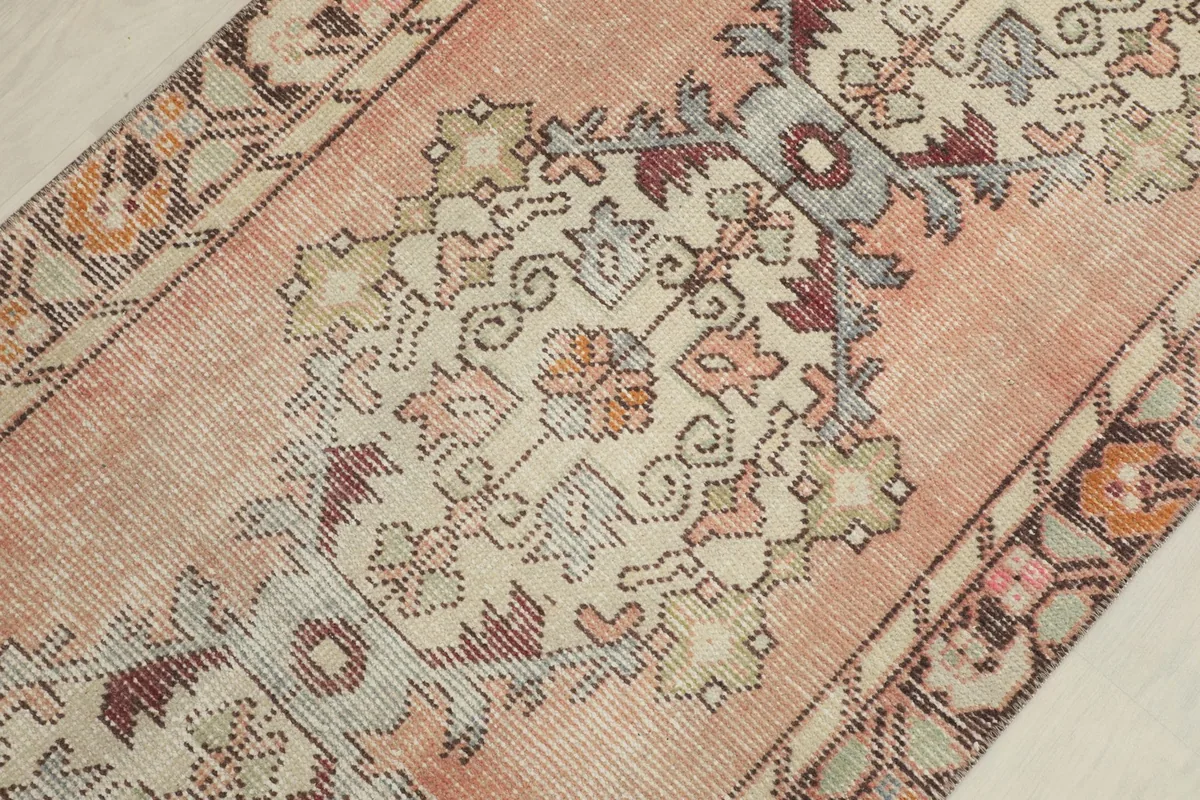 Detailed view of the central geometric floral motif in ivory, rose, and brown