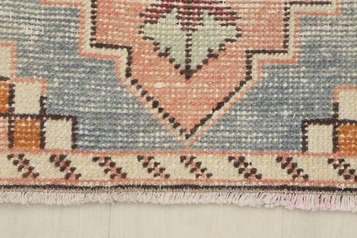 Detail of the border and fringe, highlighting the blue and rose tones