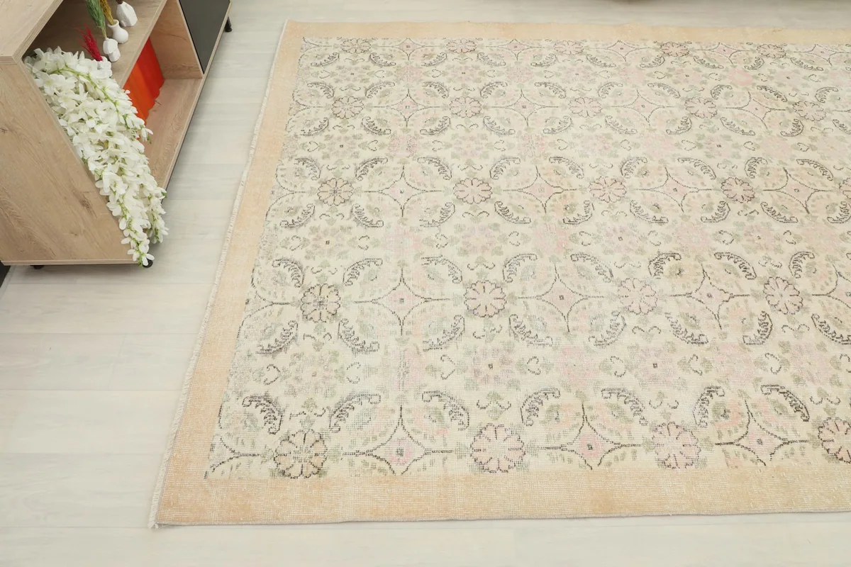 Close-up angled view of the rug's pattern and border, showing the subtle pink and green accents.